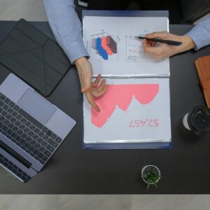 Business professionals discussing financial graphs at a desk with laptop and documents.